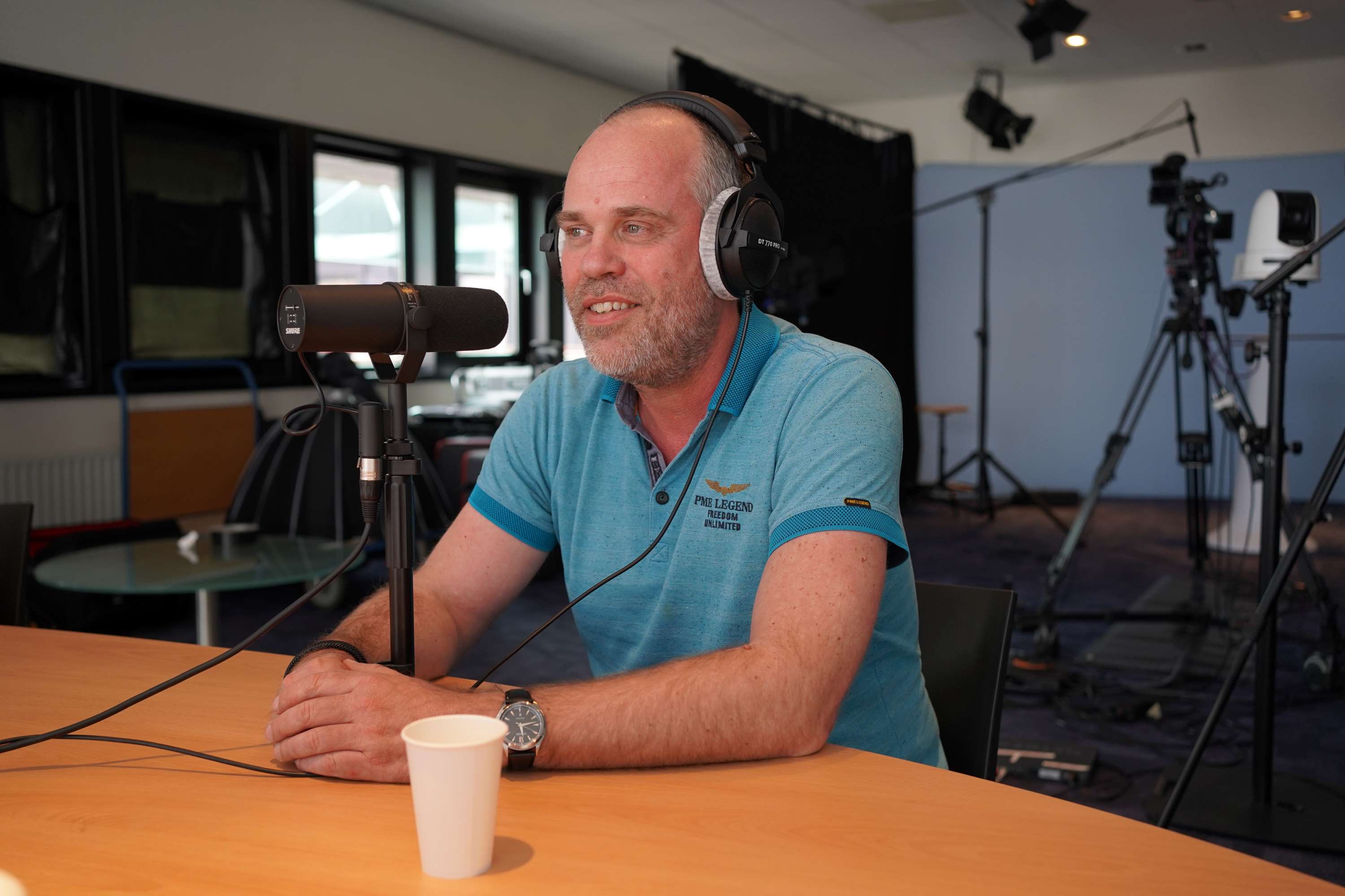 Martin wordt geïnterviewd. Hij heeft een koptelefoon op en praat in een microfoon.